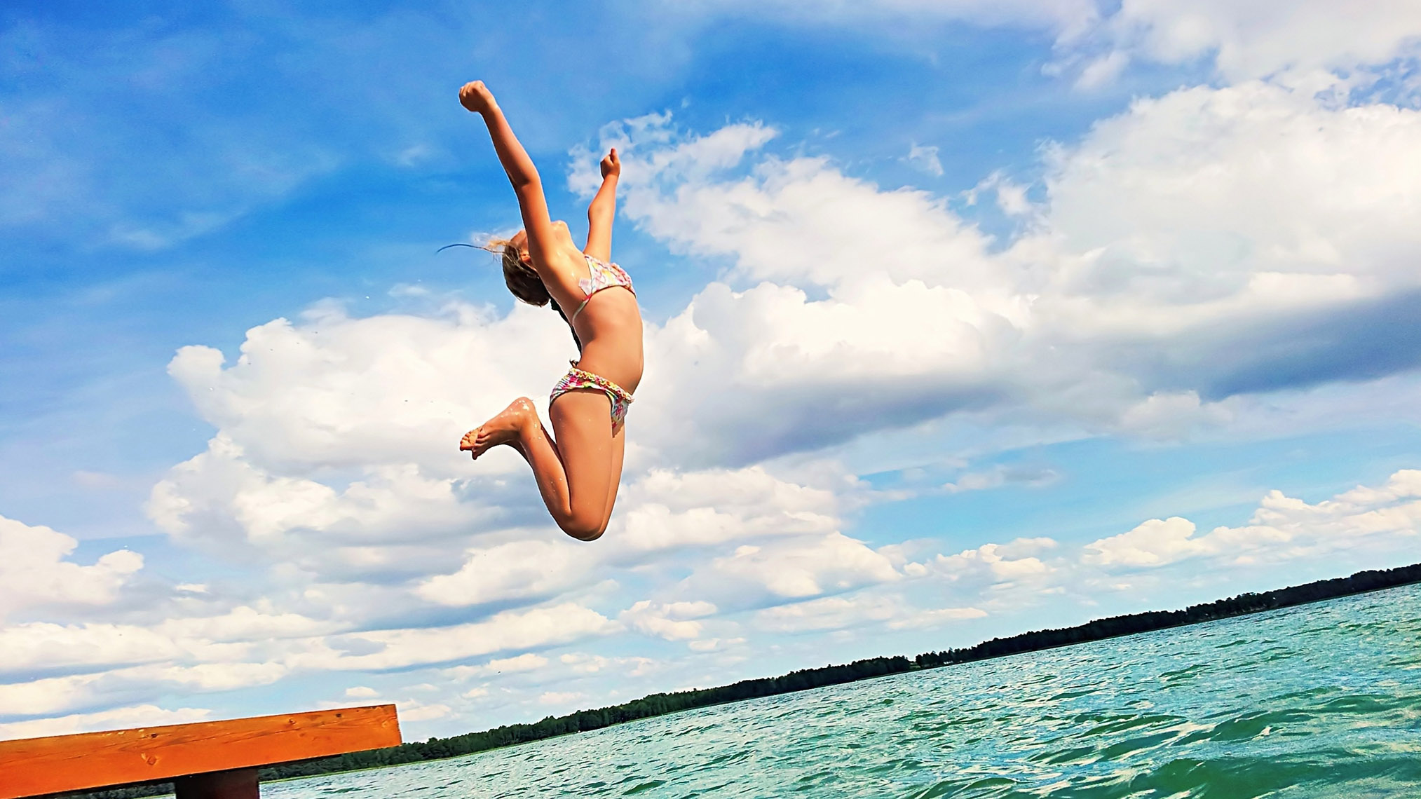 Mädchen springt begeistern in einen See