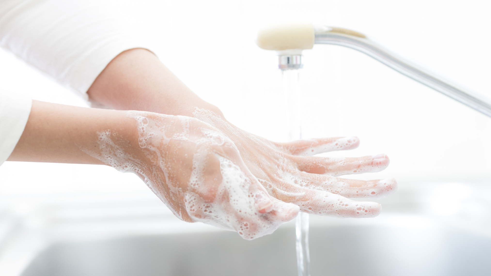 Frau wäscht ihre Hände gründlich unter einem Wasserhahn