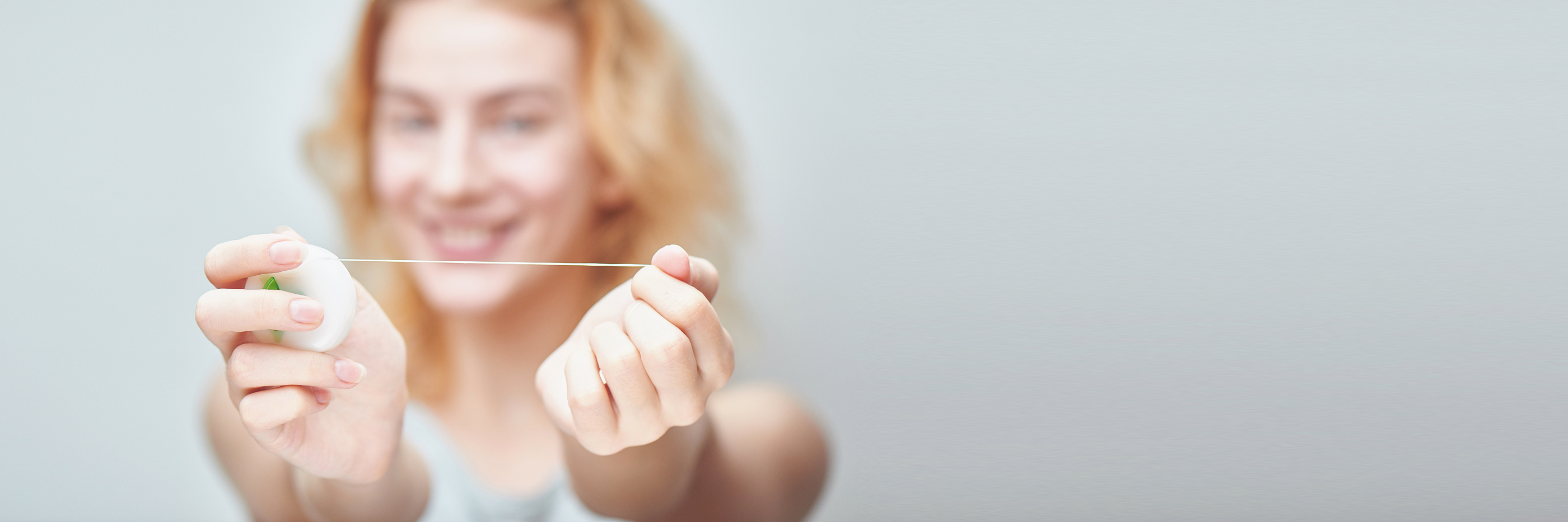 Junge Frau hält Zahnseide in die Kamera