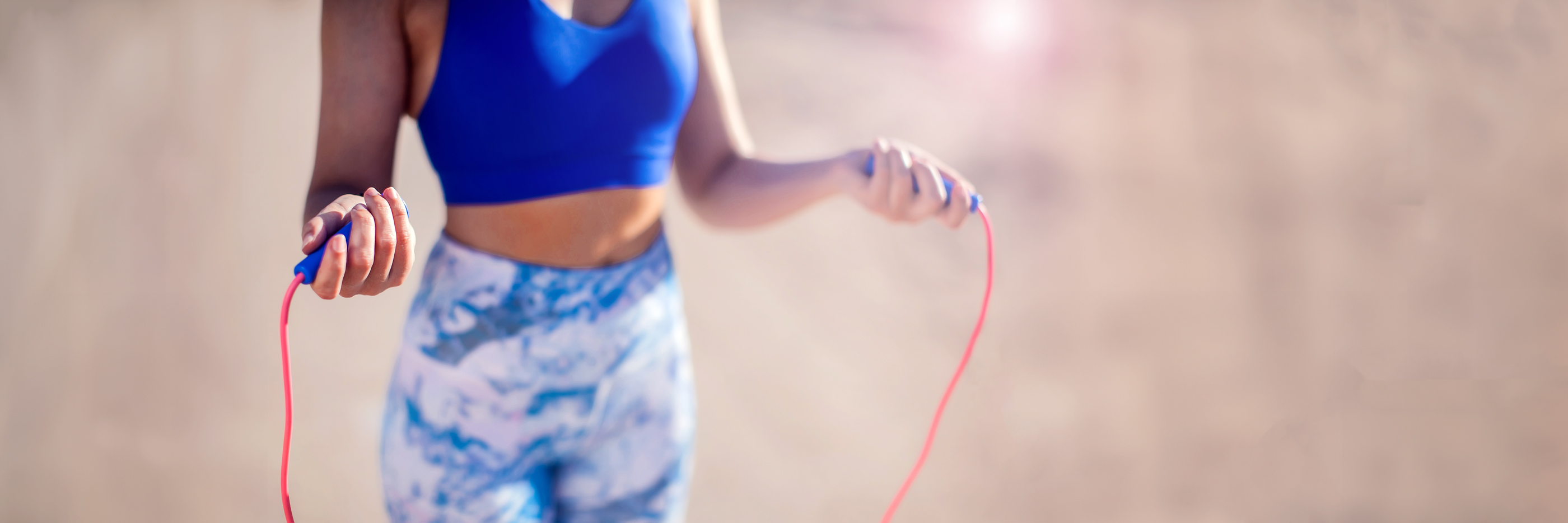 Sportlerin in blauer Kleidung hält ein Springseil in den Händen