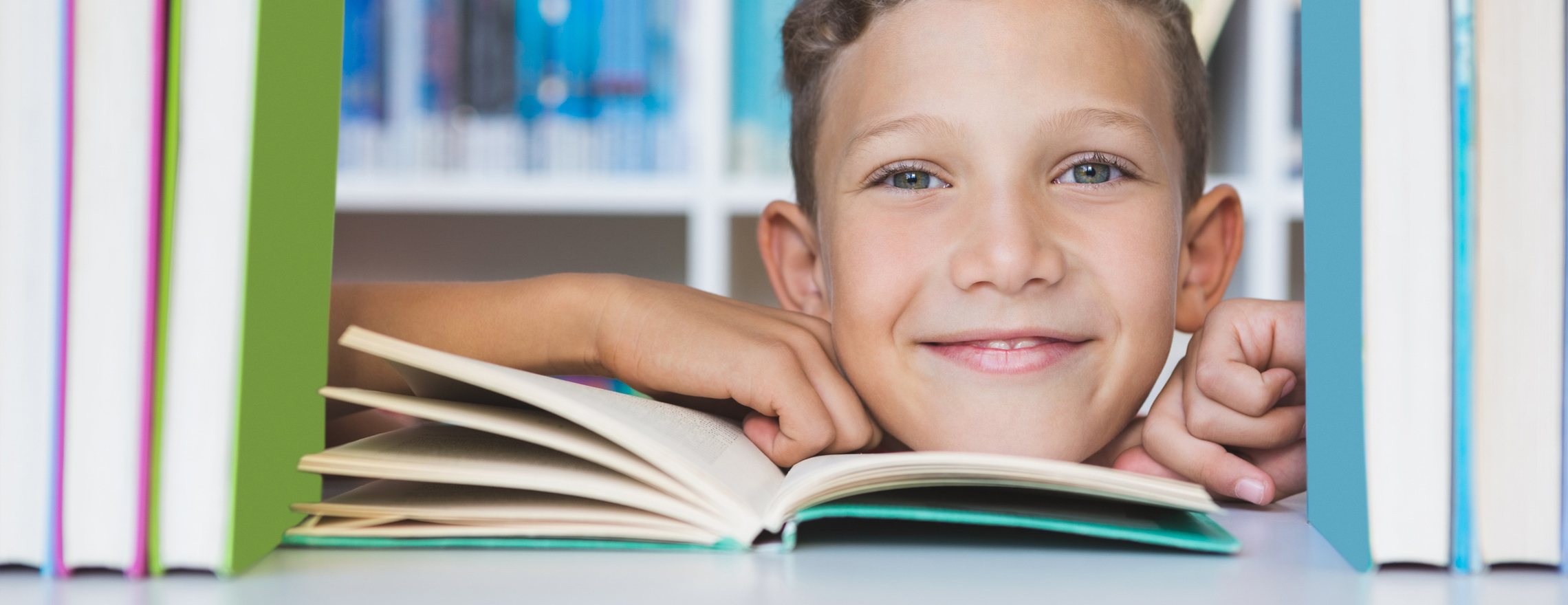 Junge schaut durch ein Bücherregal hindurch